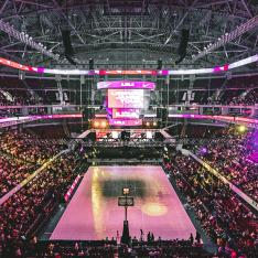 Picture of a full basket ball stadium lit with purple and pink lights